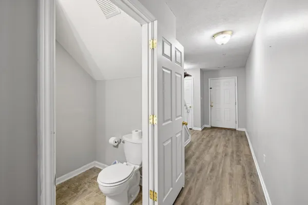 a view of a hallway with toilet and wooden floor