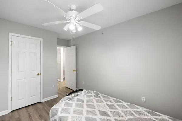 an empty room with wooden floor and fan