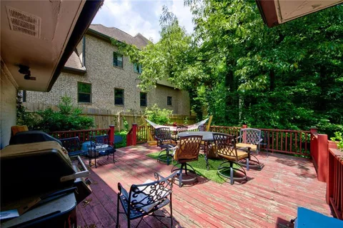 a view of deck with table and chairs barbeque potted plants and wooden fence