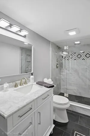 a bathroom with a granite countertop toilet a sink and a mirror