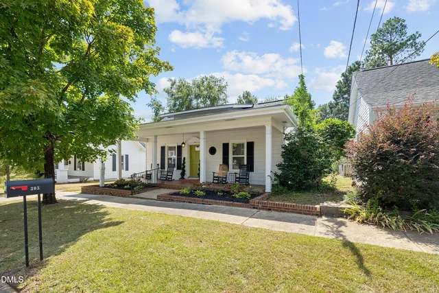 a view of a white house with swimming pool lawn chairs and a potted plants