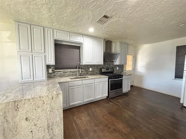 a kitchen with granite countertop a stove a sink and a microwave