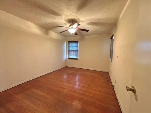 a view of a room with a ceiling fan and wooden floor
