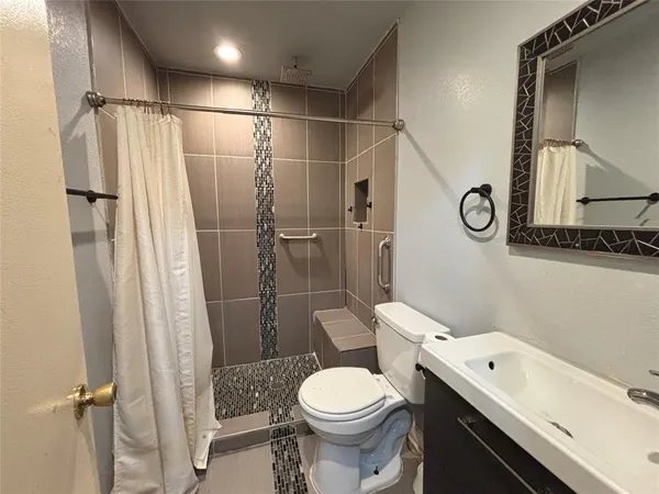 a white toilet sitting next to a bathroom sink and a shower