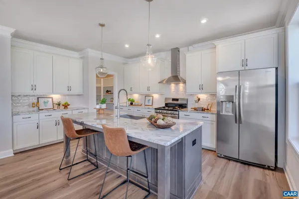a kitchen with kitchen island a white counter top space a refrigerator cabinets and a wooden floor