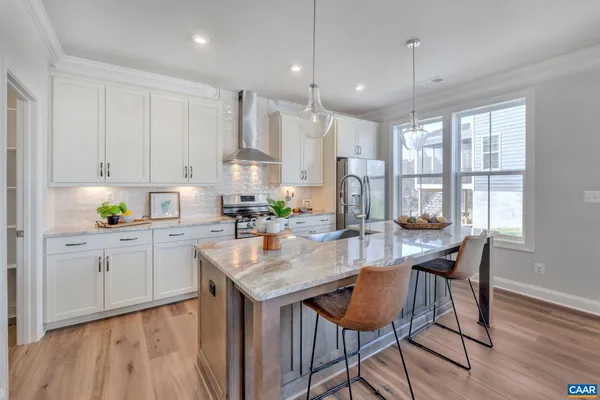 a kitchen with stainless steel appliances granite countertop a table chairs sink and cabinets