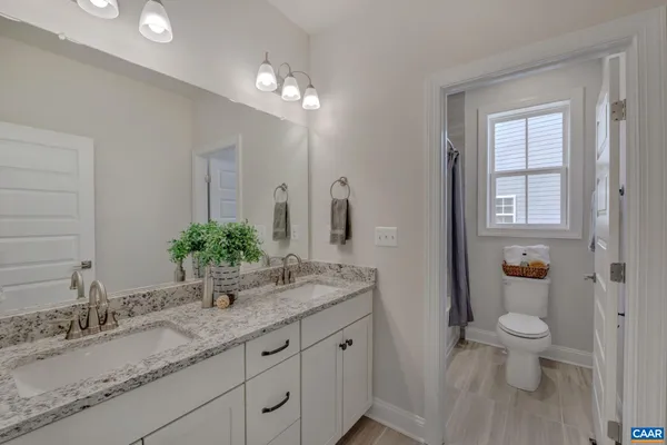 a bathroom with a granite countertop sink a toilet and mirror