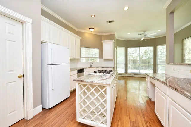 a kitchen with a refrigerator a stove a sink and wooden floor