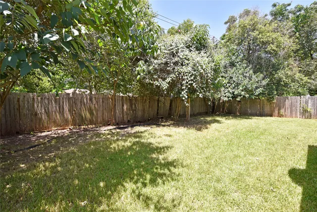 a view of a backyard with large tree and wooden fence