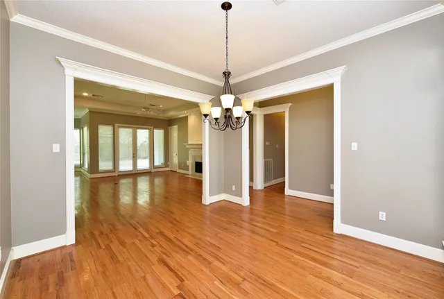 a view of a room with wooden floor chandelier and windows