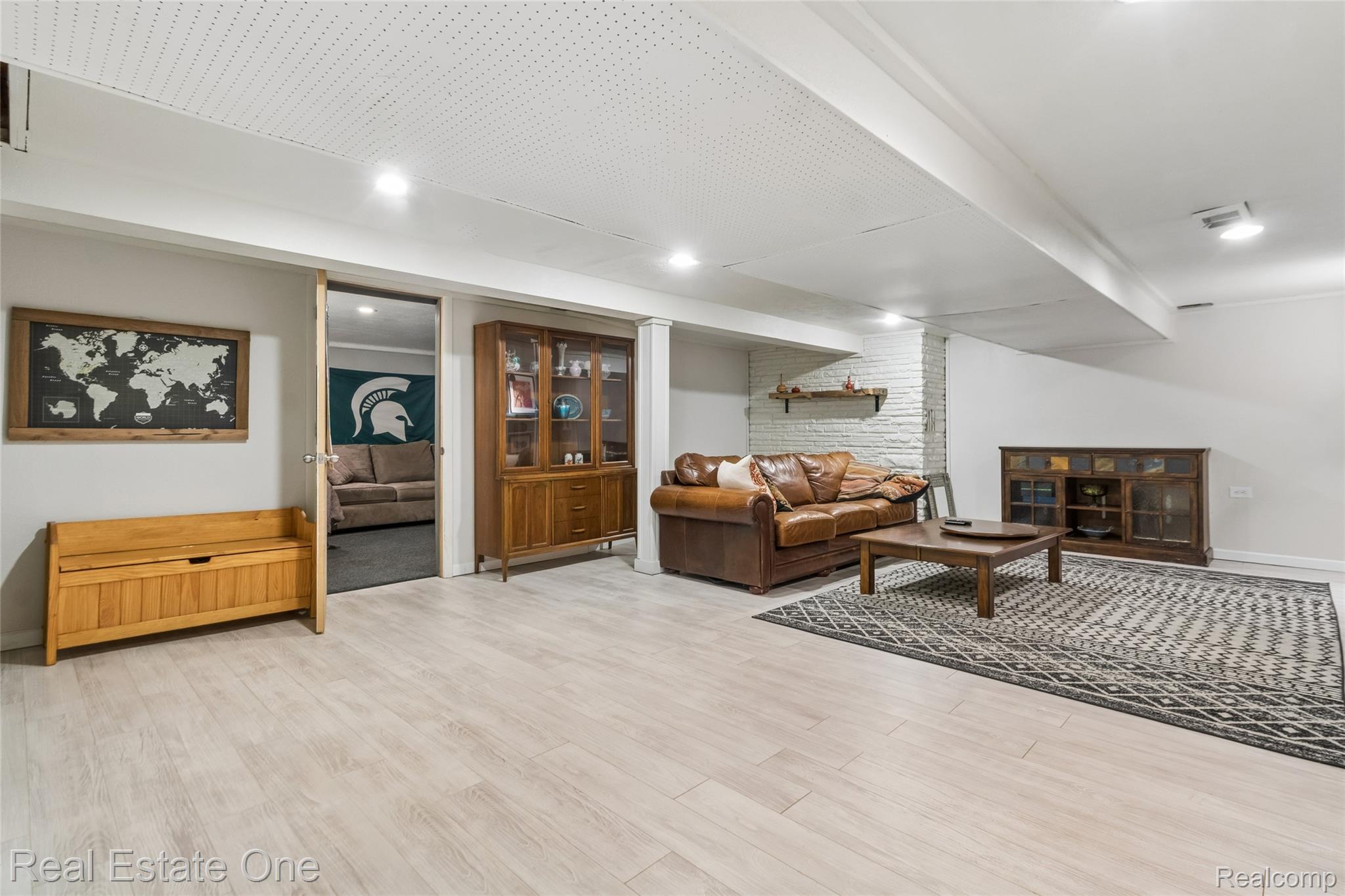 2189 Devonshire Road Bloomfield Hills, MI 48302 - Photo 34 of 50 Spacious lower-level area with light wood-finish flooring, recessed lighting, and a painted brick accent wall