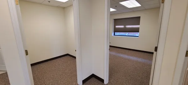 a view of an empty room with wooden floor and mirror