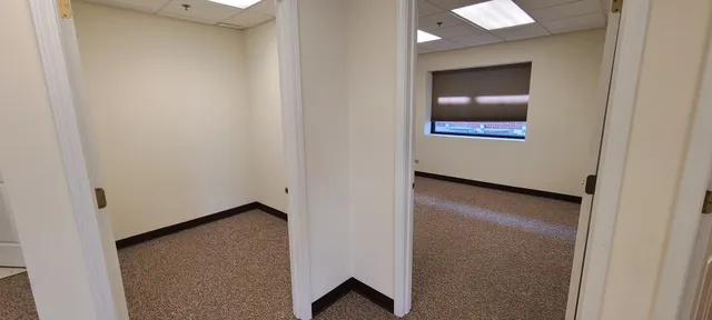 a view of an empty room with wooden floor and mirror
