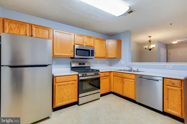 a kitchen with stainless steel appliances granite countertop a refrigerator a stove top oven a sink and dishwasher