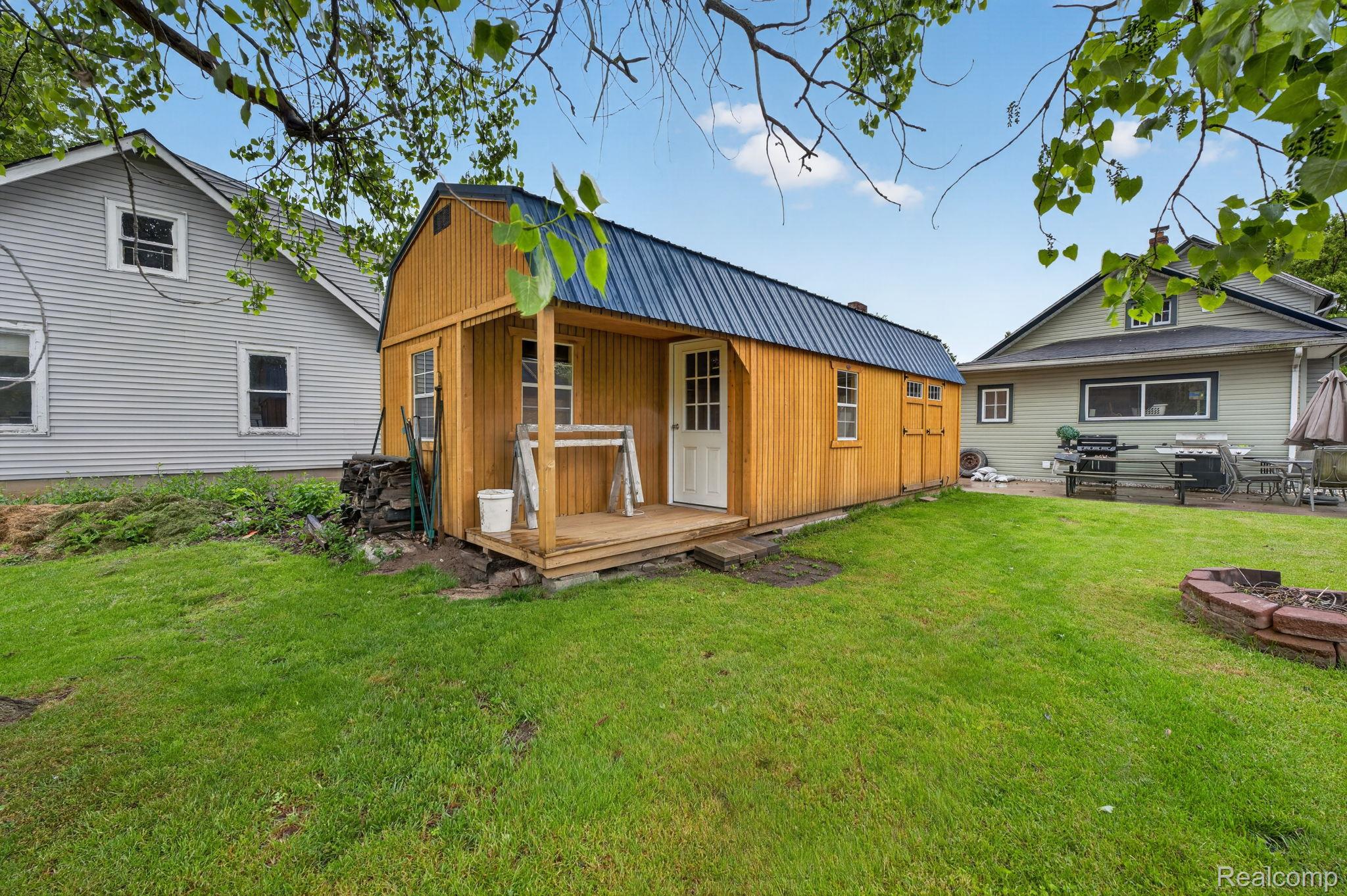 304 West Ridge Street Owosso, MI 48867 - Photo 34 of 45 Back of house featuring an outdoor structure, a metal roof, a lawn, and a gambrel roof