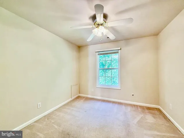 an empty room with chandelier fan and windows