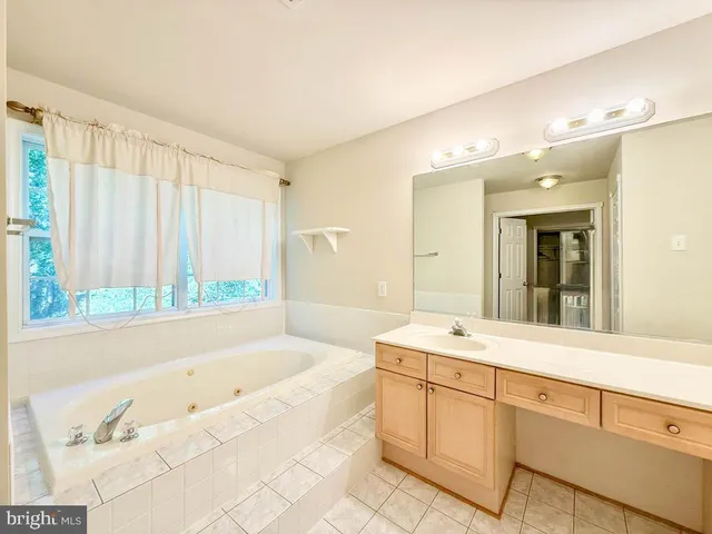 a spacious bathroom with a tub sink and mirror