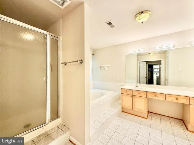 a bathroom with a tub shower sink vanity and a mirror