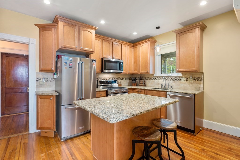 a kitchen with stainless steel appliances granite countertop a refrigerator a stove and a wooden floors