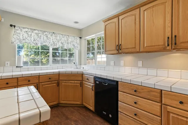 a kitchen with granite countertop a sink window and cabinets
