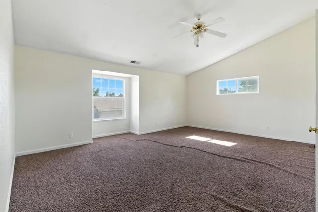 an empty room with a ceiling fan and a window