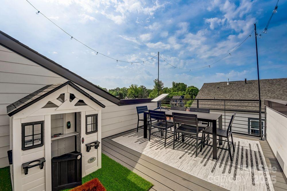 a view of a roof deck with table and chairs with wooden floor and fence