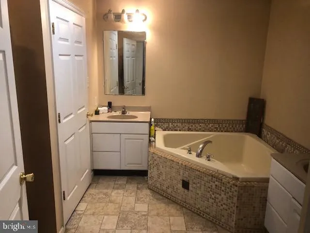 a spacious bathroom with a tub sink and mirror