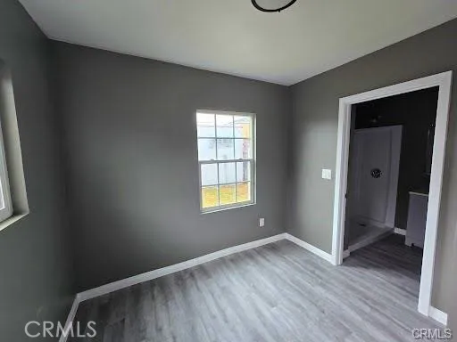 a view of an empty room with window and wooden floor