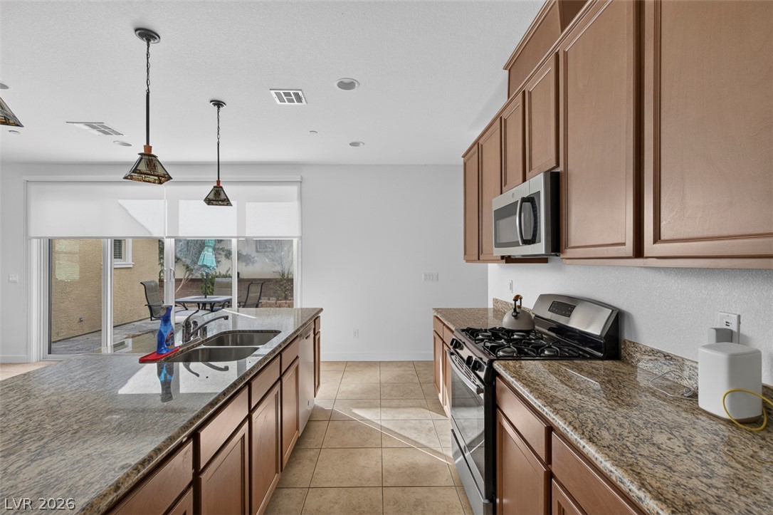 1100 East Sunset Road Henderson, NV 89011 - Photo 12 of 58 A well-equipped kitchen features a generous island and modern appliances, opening to an inviting outdoor space.