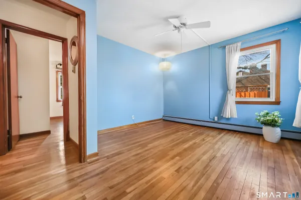 a view of an empty room with wooden floor and a window