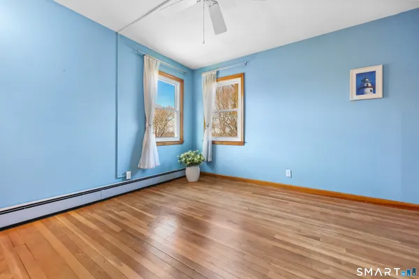 a view of an empty room with a window and wooden floor