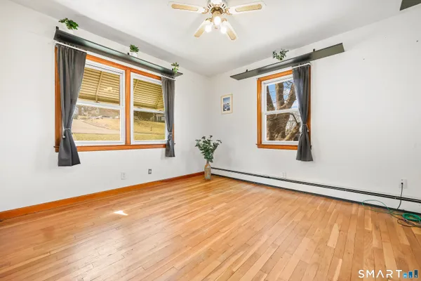 a view of an empty room with wooden floor and a window