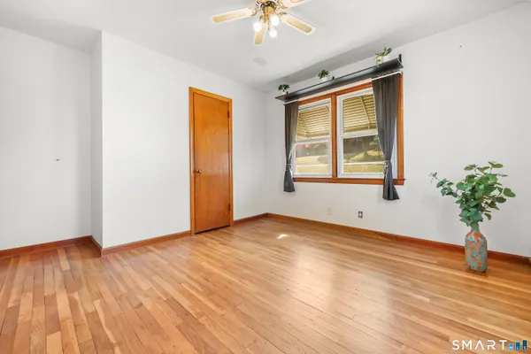 a view of an empty room with wooden floor and a window