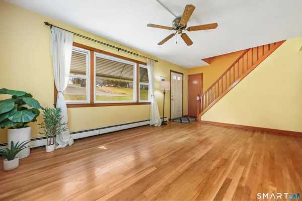 a view of empty room with wooden floor and fan