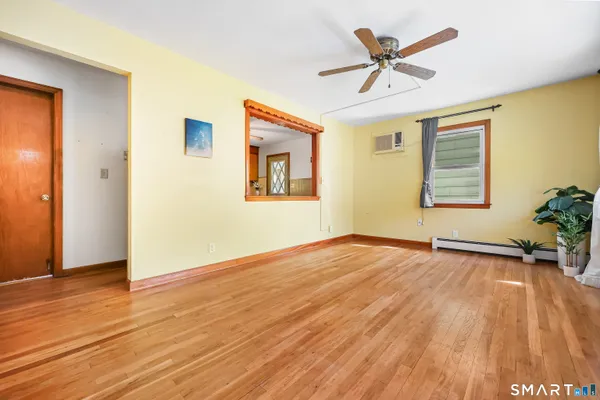 a view of empty room with wooden floor and fan