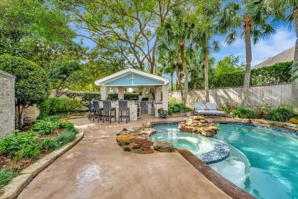 a view of a backyard with plants and a table and chairs under an umbrella