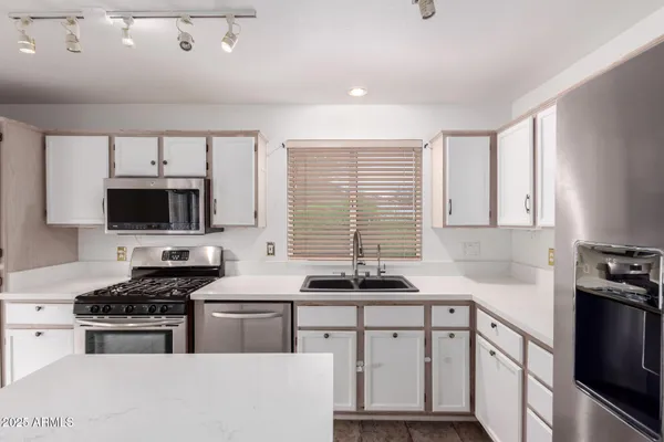 a kitchen with stainless steel appliances a sink dishwasher a stove a microwave and cabinets