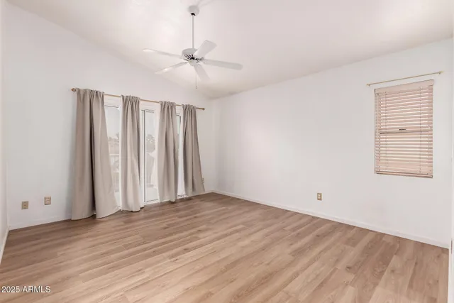 an empty room with wooden floor fan and windows