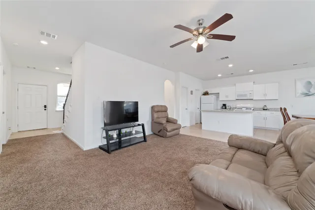 a living room with furniture and a flat screen tv with kitchen view