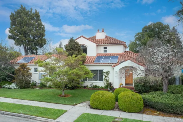 a front view of a house with a garden and trees