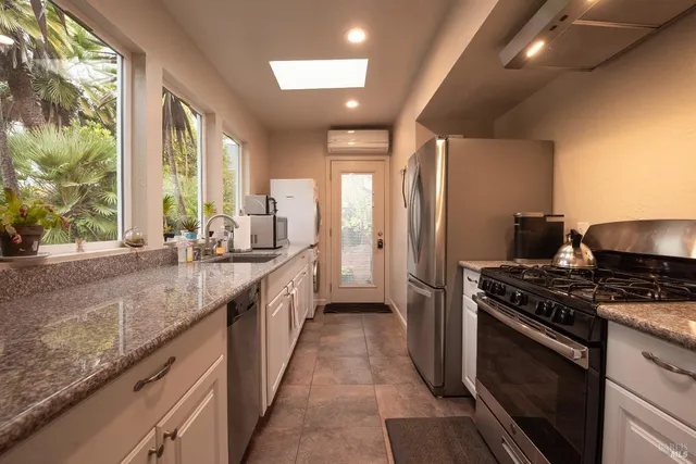 a kitchen with stainless steel appliances granite countertop a stove a sink and a refrigerator