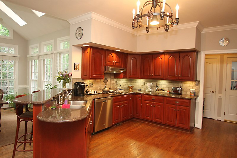 12301 Staunton Court Raleigh, NC 27613 - Photo 7 of 25 Kitchen is well lit with can lighting above cabinets in addition to light under cabinets for granite countertops and tiled backsplash. Kitchen