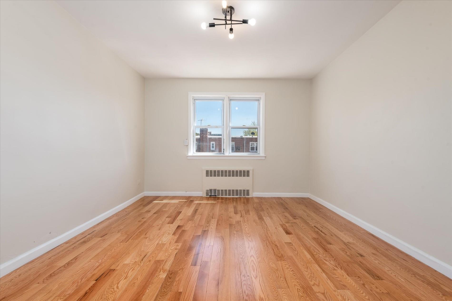 150-20 77th Avenue Queens, NY 11367 - Photo 14 of 24 wooden floor in an empty room with a window