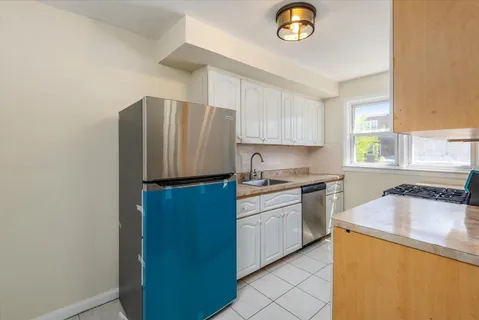 a kitchen with granite countertop a refrigerator a stove a sink and a window