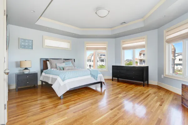 a spacious bedroom with a bed and a flat tv screen on dresser