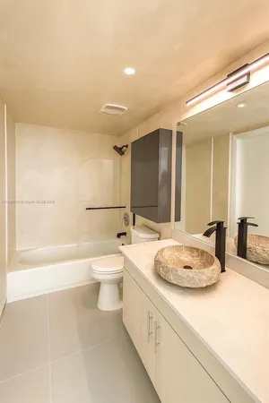 a bathroom with a granite countertop sink toilet mirror and bathtub
