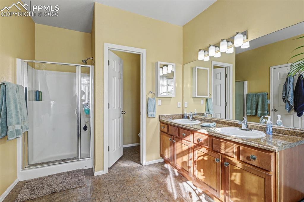 7858 Chasewood Loop Colorado Springs, CO 80908 - Photo 17 of 40 a bathroom with a granite countertop sink a mirror and a shower