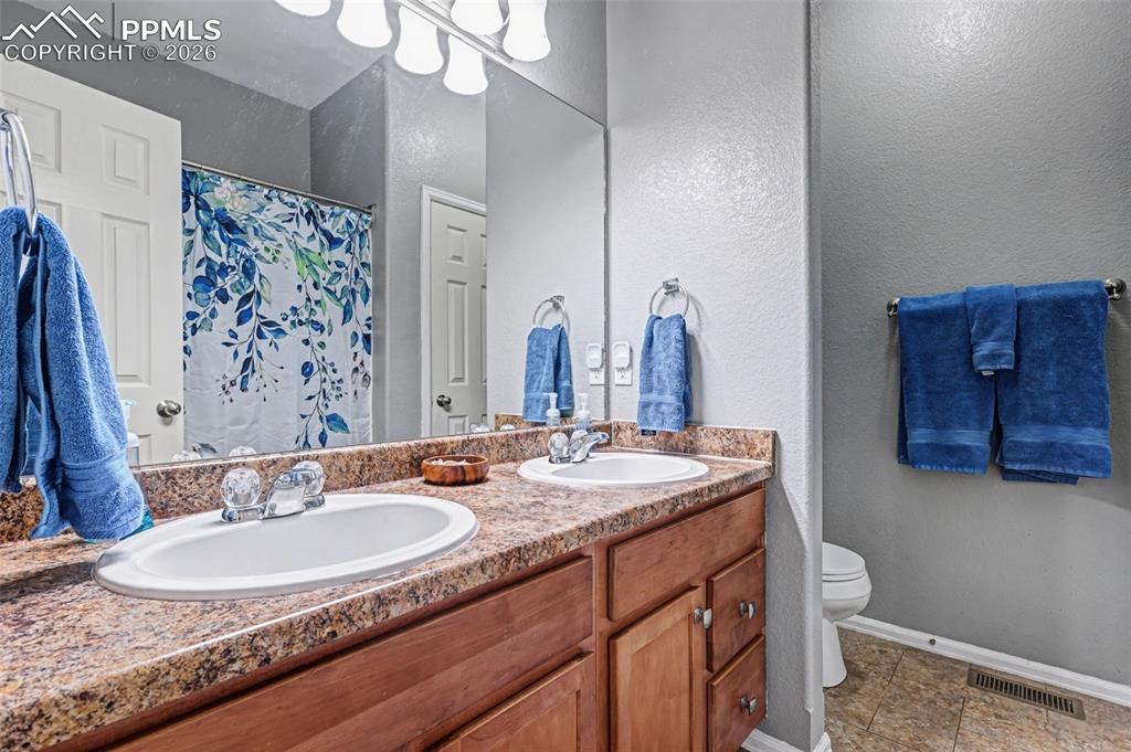 7858 Chasewood Loop Colorado Springs, CO 80908 - Photo 21 of 40 a bathroom with a granite countertop sink a toilet and a mirror