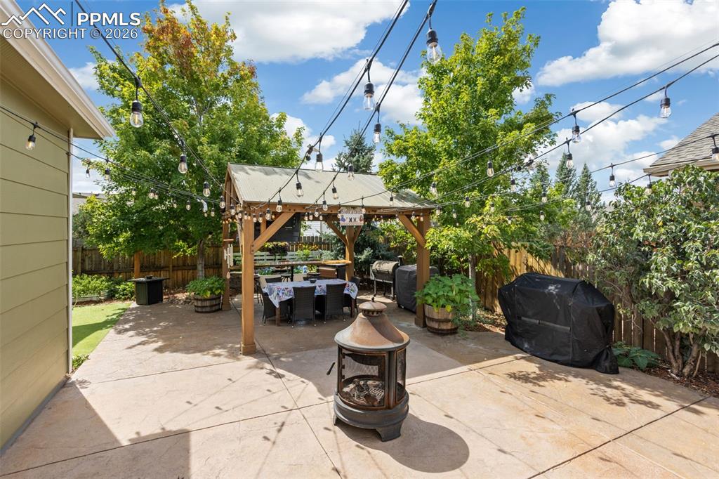 7858 Chasewood Loop Colorado Springs, CO 80908 - Photo 34 of 40 a view of a patio with table and chairs potted plants and a large tree