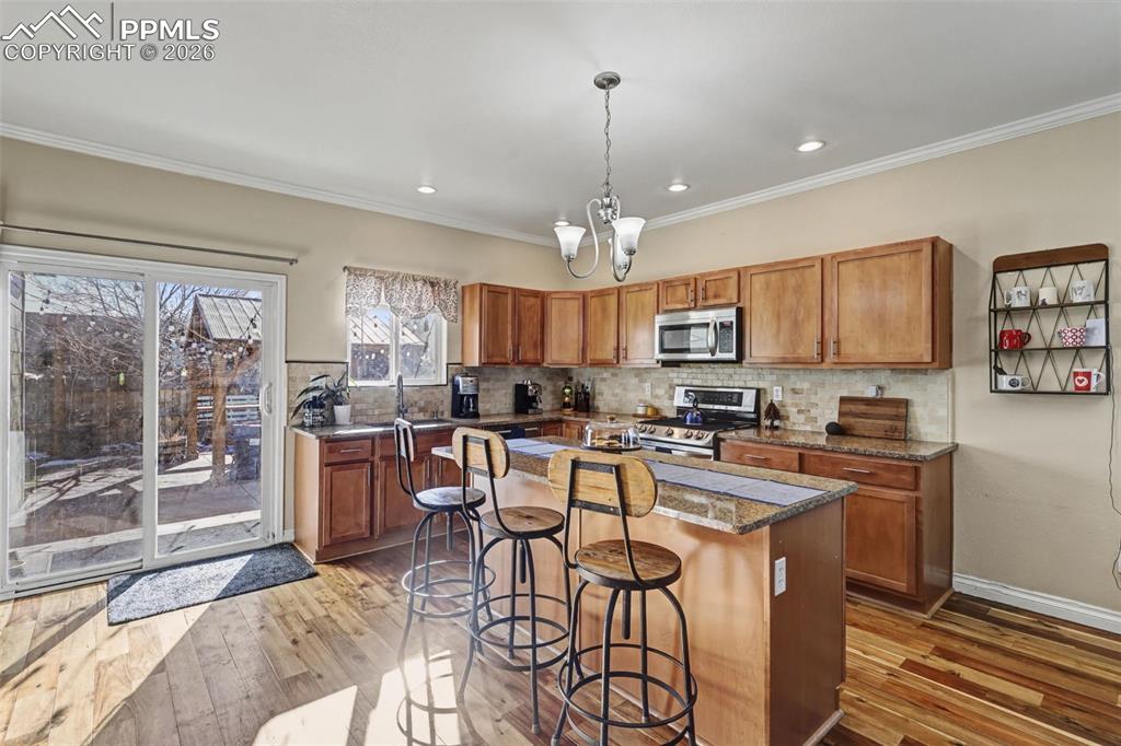 7858 Chasewood Loop Colorado Springs, CO 80908 - Photo 9 of 40 a kitchen with stainless steel appliances granite countertop a stove top oven a sink dishwasher a dining table and chairs with wooden floor